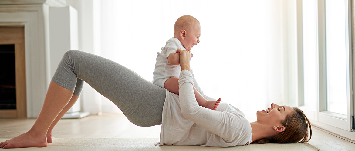 a woman does a glute bridge with her baby