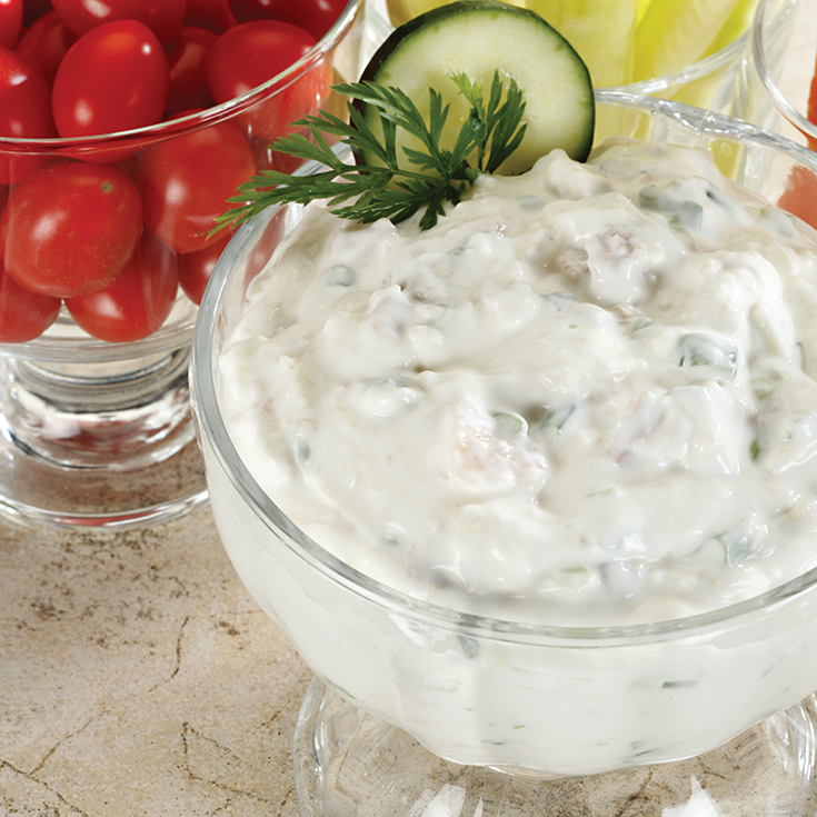 clam dip in a glass serving bowl with dill garnish